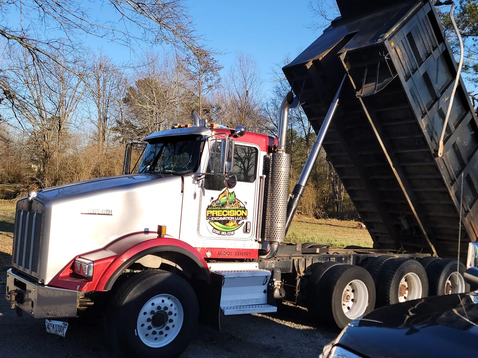 Dump trailer tipping a load of red dirt on a job