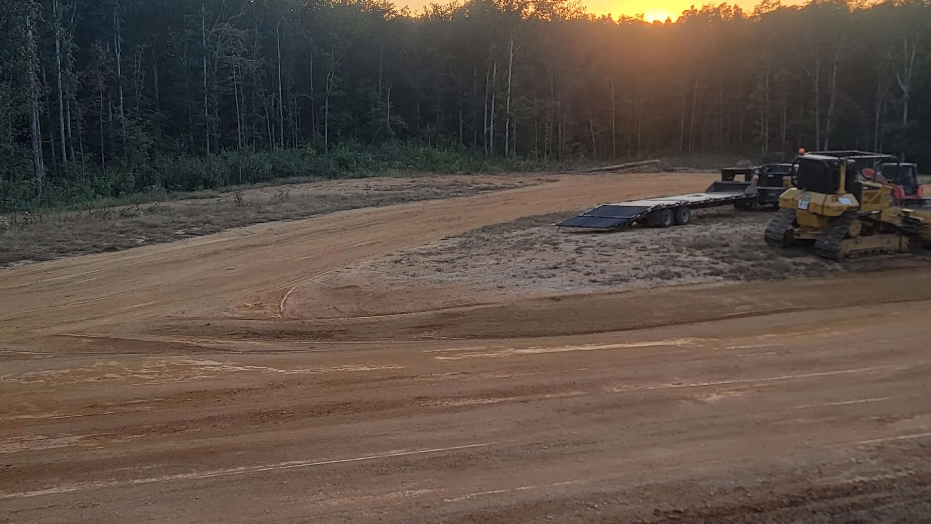 Freshly graded building pad ready for rock, our machines parked at the treeline on a North Alabama job