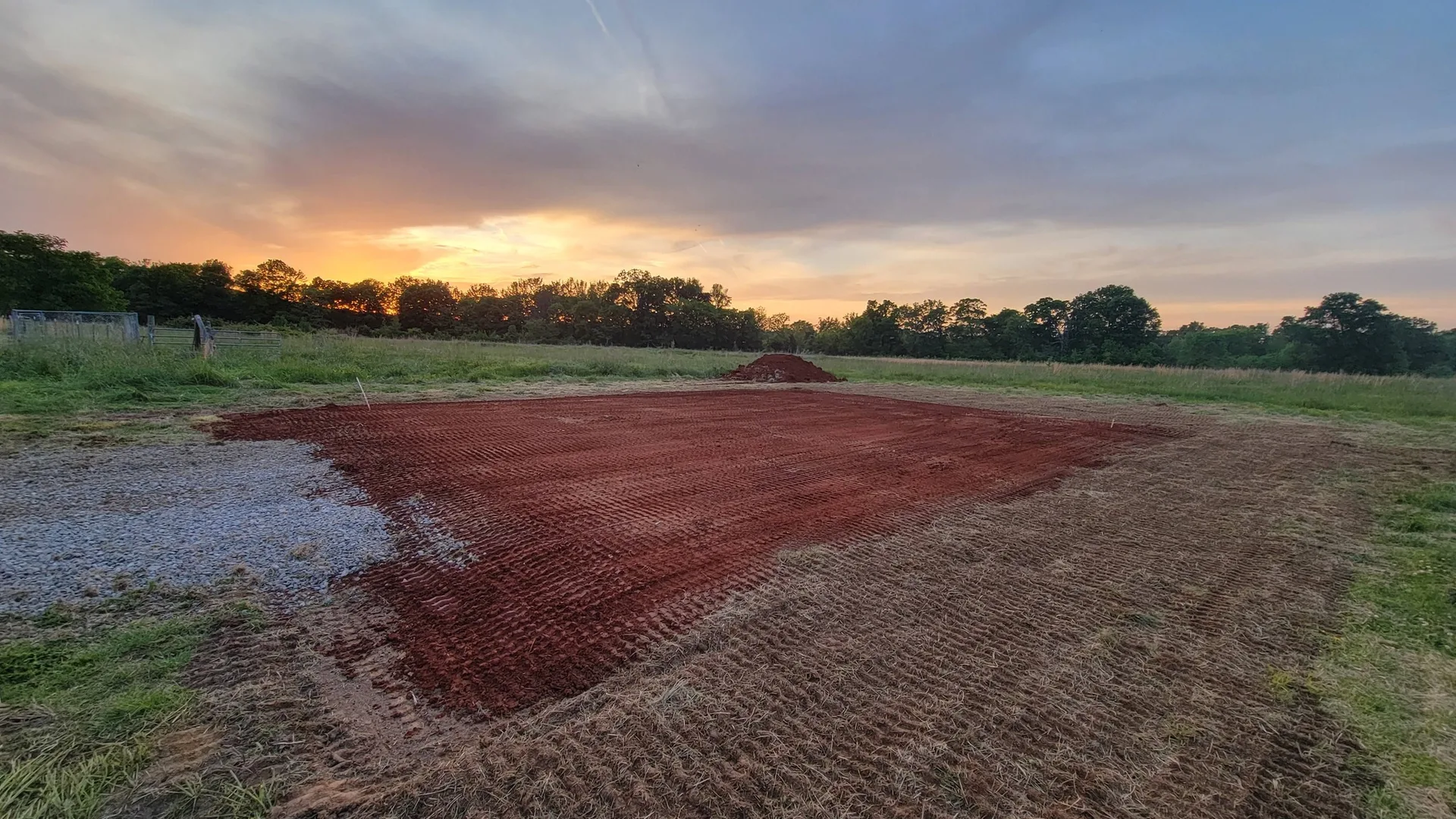 Graded ground at sunset with the treeline behind