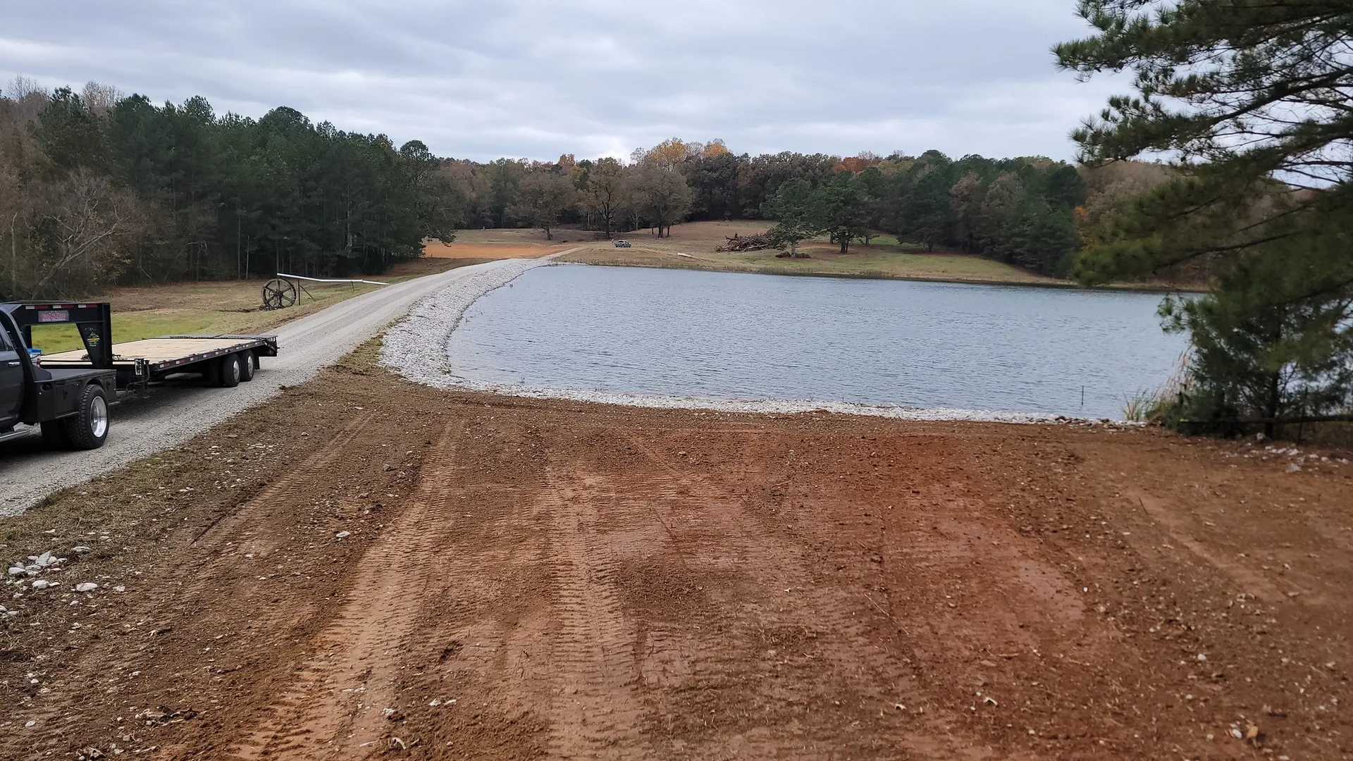 Excavator digging a new farm pond with water standing in the fresh cut on wooded rural land
