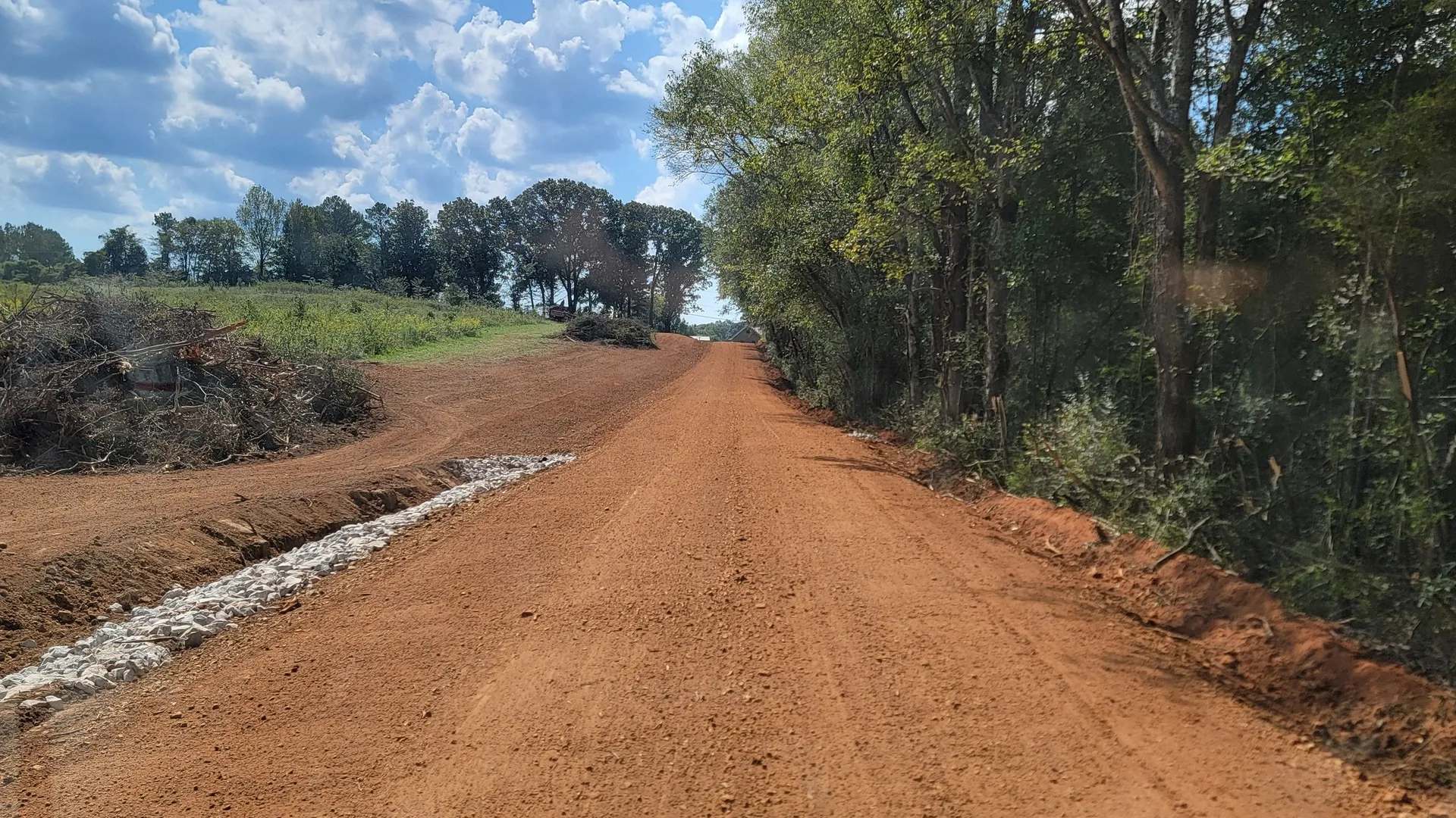 Red dirt road built with a rip rap ditch along the side