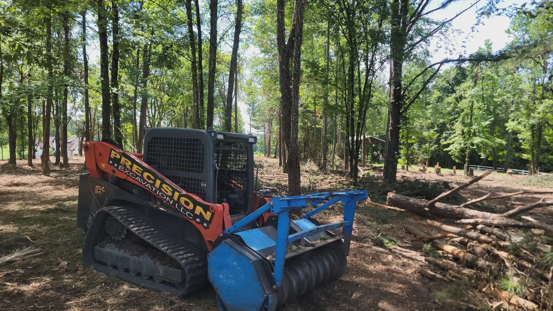 Track loader with a forestry mulching head grinding brush on a wooded Tennessee Valley hillside